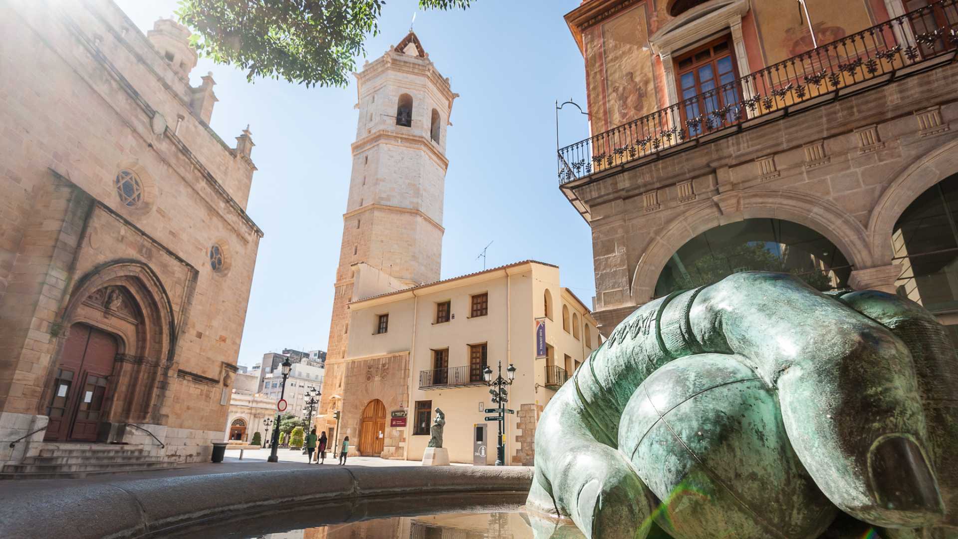 A square in the old town of Castellón with a bell tower and a bronze sculpture