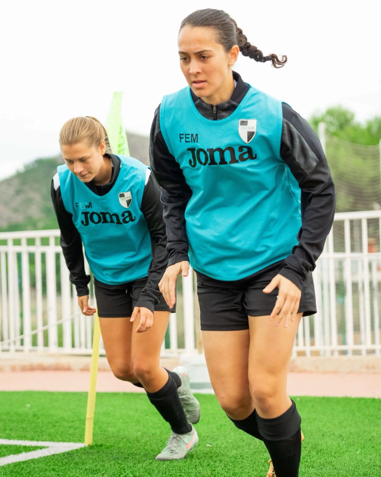 Two women's academy players running a conditioning drill in training bibs