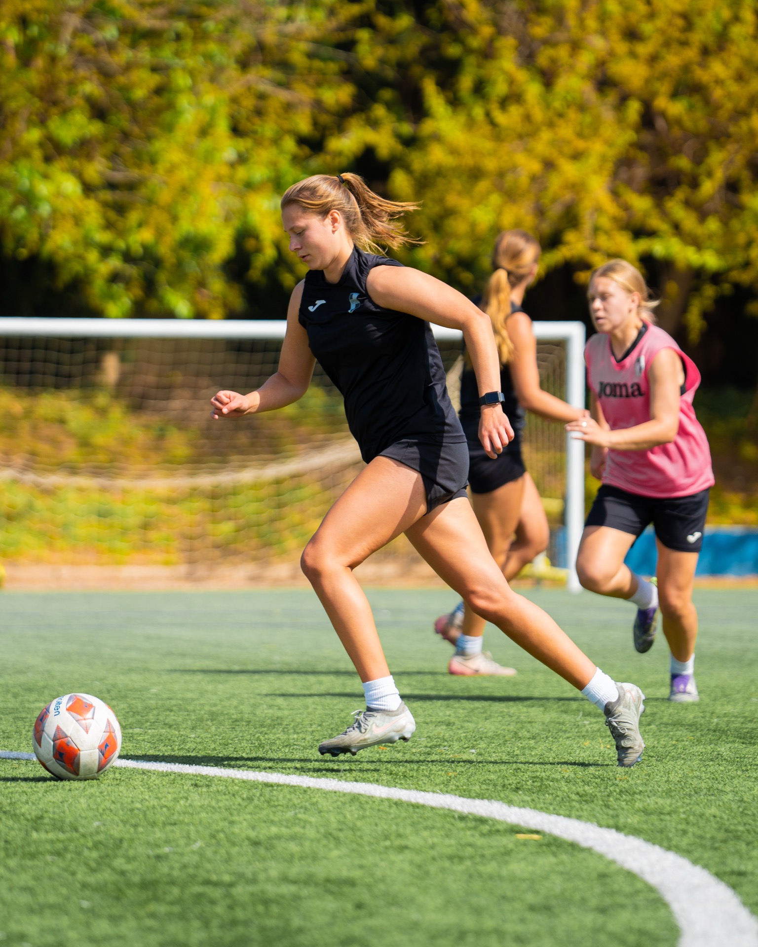 A women's academy player running onto the ball in a training drill