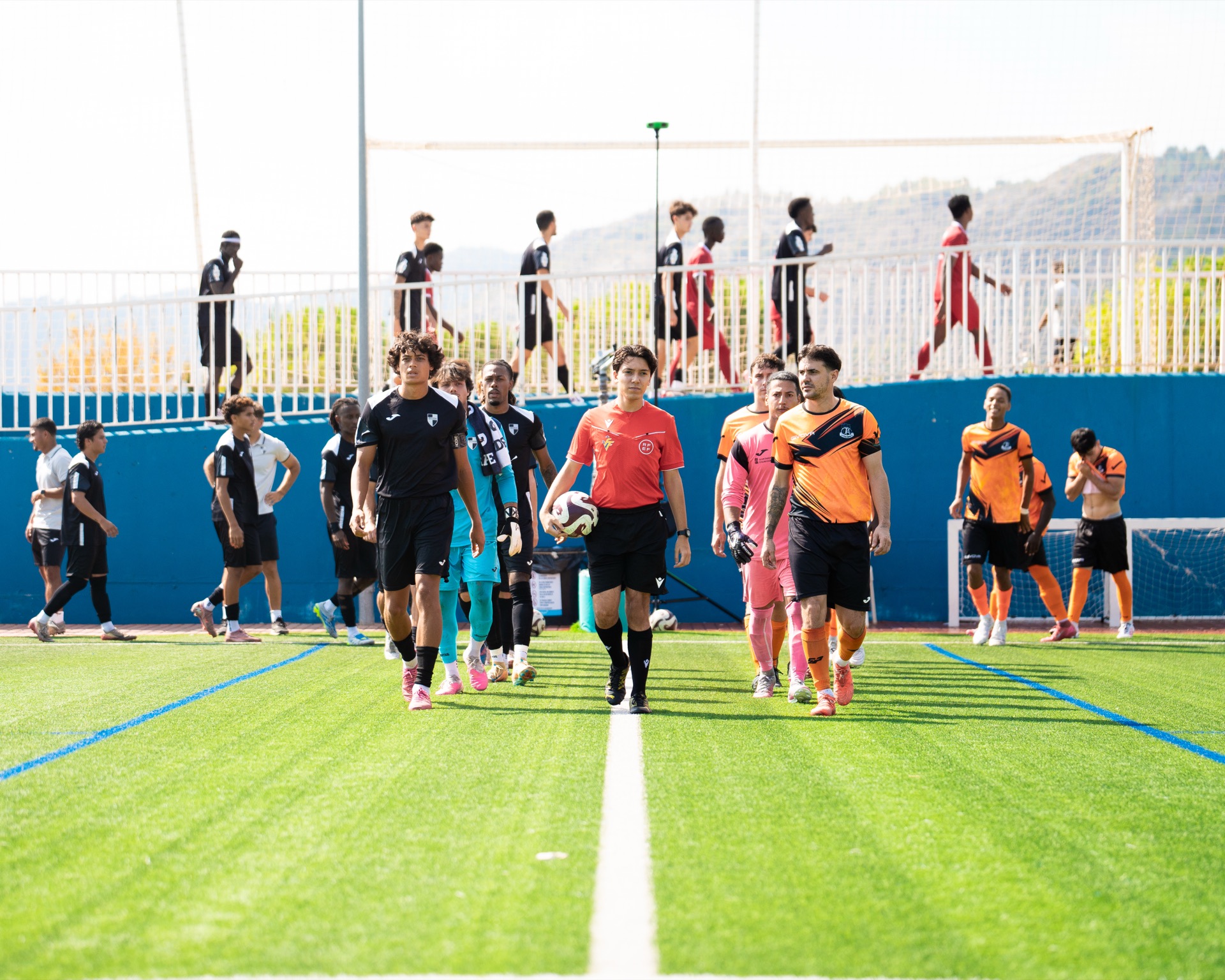 Los jugadores de la academia masculina salen al campo junto al árbitro antes de un partido